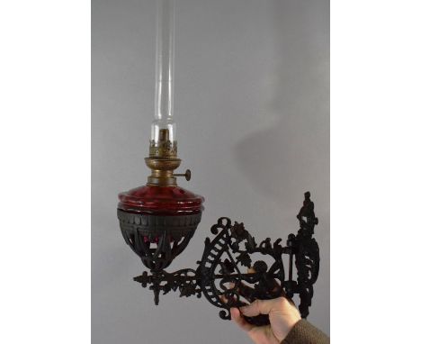 A Victorian Pierced Metal Wall Mounting Oil Lamp Holder Complete with Lamp Having Cranberry Glass Reservoir