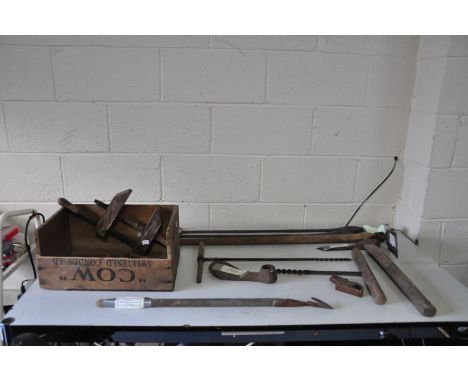 A VINTAGE WOODEN BOX CONTAINING VINTAGE TOOLS including a 19C Dutch Hoe, axe, a Muck Knuckler, a wooden clamp, handled Awls e