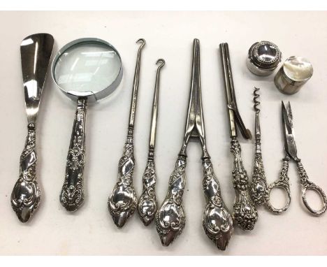 Group of silver handled items including a magnifying glass, button hooks, glove stretchers, scissors and two pill pots 