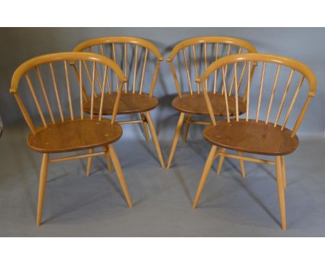A Set Of Four Ercol Blonde Elm and Beech Armchairs each with a stick back above a panel seat, raised upon turned legs with st