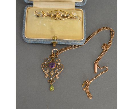 An Edwardian 9ct. Gold Pendant Of Scroll Form set with a central amethyst, seed pearls and drop emeralds, with yellow metal l