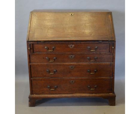 A George III Oak Bureau, the fall front enclosing drawers and pigeon holes with a central drawer above four long drawers with