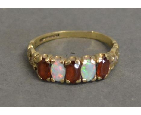 A 9 ct. Opal And Garnet Set Ring With Two Opals And Three Garnets, within a pierced setting 