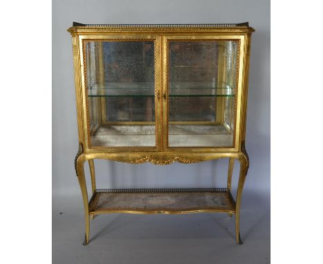 A Late 19th. Early 20th Century French Gilded and Gilt Metal Mounted Display Cabinet with a low brass galleried top above two