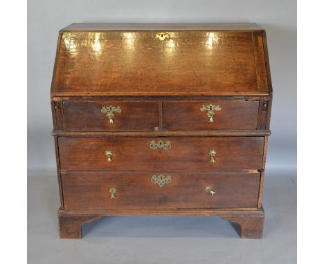 A George III Oak Bureau The Fall Front Enclosing A Fitted Interior above two short and two long drawers with brass drop handl