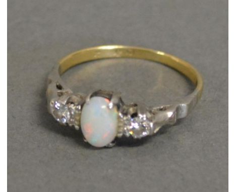 An 18 ct. Gold, Platinum, Opal And Diamond Ring with a central cabochon opal flanked by diamonds, within a pierced setting 