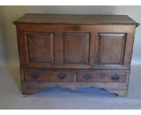 A George III Oak Mule Chest, the hinged moulded top above a three panel front and two drawers with swan neck handles flanked 
