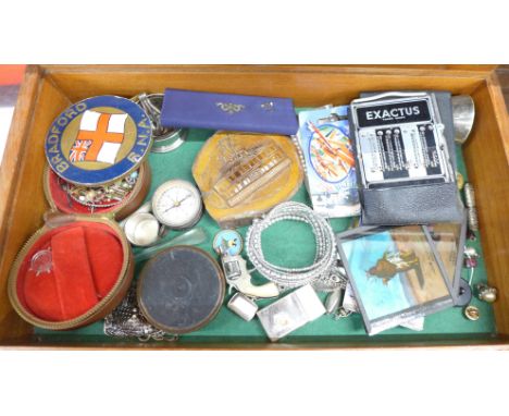 A display case with compass, buttons, bracelet, lighter and other items 