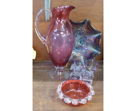 A cranberry glass jug and bowl, a carnival glass bowl and a pair of glass shoes 