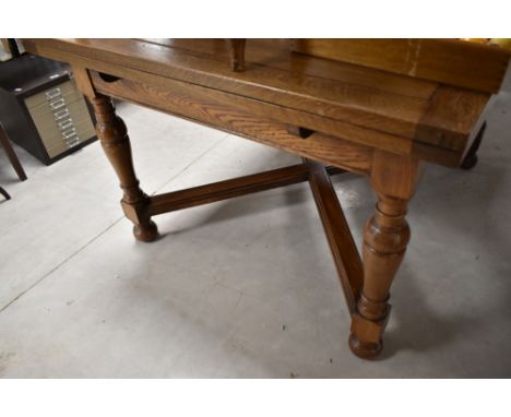 An early 20th Century oak drawer leaf dining table and set of six ladder back dining chairs of complimentary design