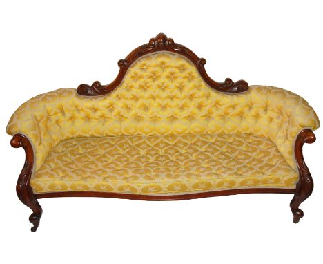 A Victorian mahogany scroll button back settee the foliate shaped frame above a serpentine seat and on foliate scroll legs, 1