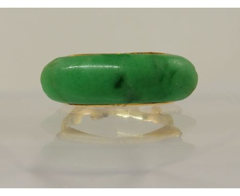 A Chinese green hardstone ring in a bright yellow metal scrolled and engraved ring mount, size of stone 23mm x 7mm, finger si