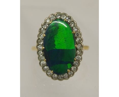 An opal doublet and diamond ring mounted in un-hallmarked yellow metal, the large opal doublet with green/blue fire is claw s