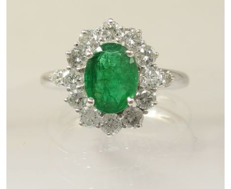 An 18ct white gold emerald and diamond ring the central emerald is 8.88mm x 6.79mm x 3.56mm, and surrounded with diamonds to 