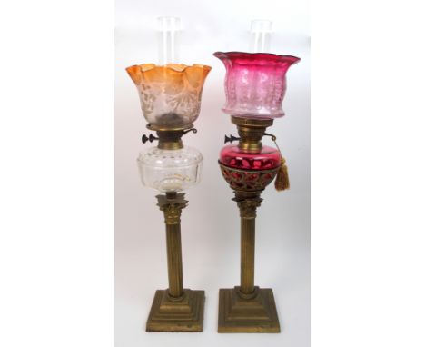 A Victorian brass and cranberry glass oil lamp the Corinthian column stem on stepped platform base, the upper fretted cup bow