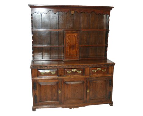 An 18th/19th Century oak dresser the three tier plate rack with scalloped canopy above a central inlaid door, the base with t