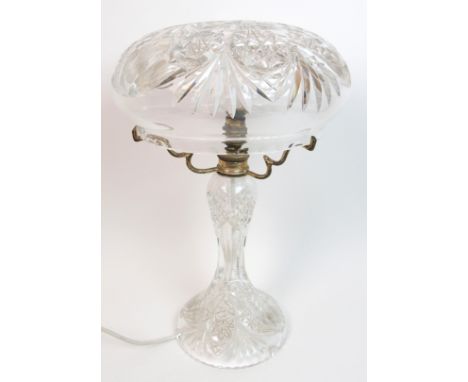 An early 20th Century crystal table lamp the cut and engraved crystal shade raised on three silver plated supports above a wa