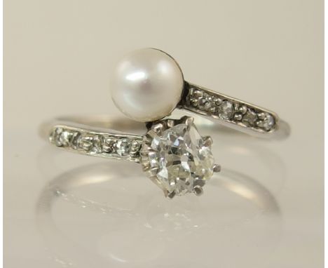 A white metal pearl and diamond ring of classic twist design the largest old cut diamond is approximately 0.30cts, twined wit