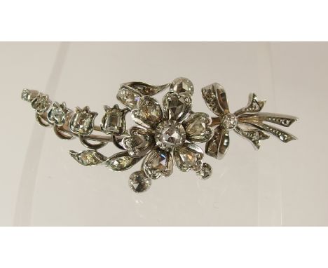 A Victorian diamond spray brooch fashioned in yellow and white metal with a stem of lily of the valley and a rose tied with a