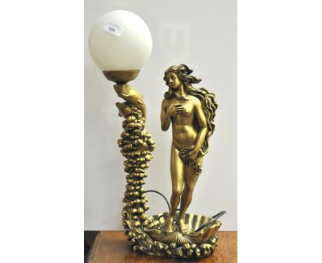A gold painted lamp, formed as Venus astride a shell, beside dolphins on waves, issuing a lamp shade, 52cm high