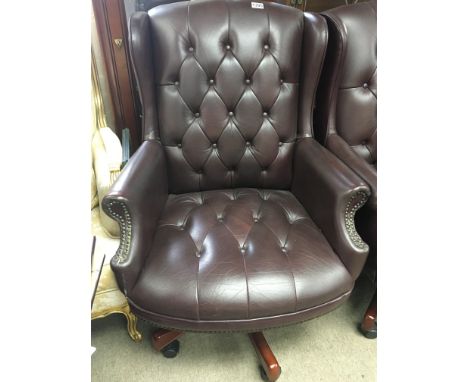 A modern leather upholstered revolving wing arm chair button back upholstery.