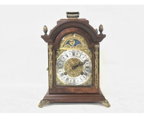 Franz Hermle Burr Walnut mantel clock with an arched dial with sun and moon phase with Roman and Arabic numerals on the face.
