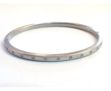 An 18ct brushed white gold bangle studded with 12 diamonds, 12.9g