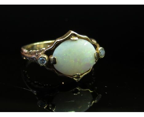 A 9ct gold opal and diamond ring, the central opal flanked by small diamonds, size K, 3.6g