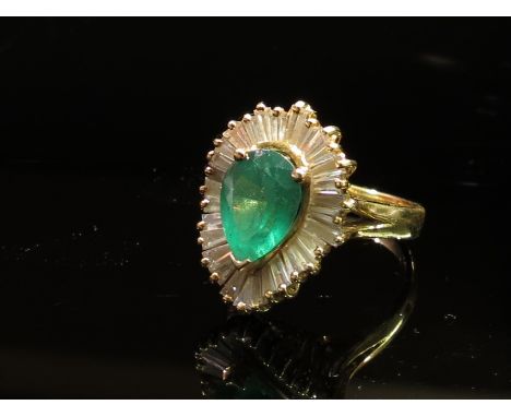 A gold diamond and emerald ring, the large pear shaped emerald framed by baguette cut diamonds in a wavy setting, shank stamp