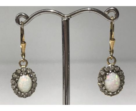 A pair of 18ct yellow gold Opal and diamond earrings. Central oval natural opals with brilliant cut diamond surrounds. 9ct go