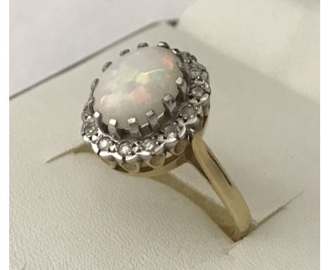 An 18ct yellow gold, Opal and diamond ring. With large oval natural opal cabochon surrounded by 14 brilliant cut diamonds. Ri