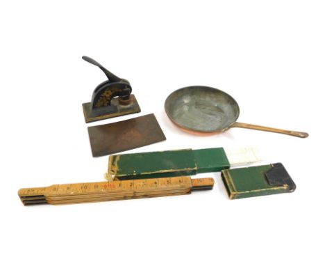 An early 20thC brass handled copper frying pan, cast iron company stamp, slide rules, a measuring stick, and a 19thC copper p