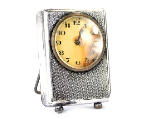 A George V silver cased mantel clock, with engine turned decoration, and a white enamel dial with metal hands, maker Spurrier