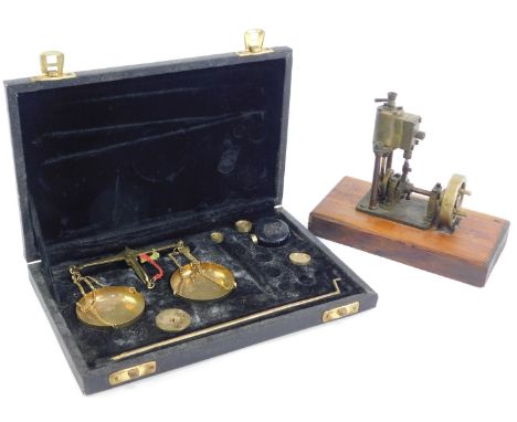 A set of gold scales, with weights, cased, together with a brass model of a pump engine on a wooden base. (2)