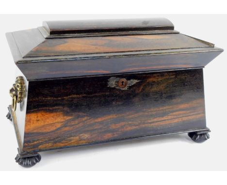 A 19thC coromandel sarcophagus shaped tea caddy, with brass lion mask ring handles, the hinged lid enclosing a cut glass tea 