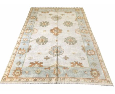 OUSHAK CARPET, 269cm x 176cm, scattered stylised palmettes on an ivory field within corresponding borders.