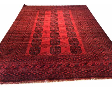 FINE AFGHAN CARPET, 390cm x 310cm, row of tribal guls on a bright ruby field within multiple geometric borders.