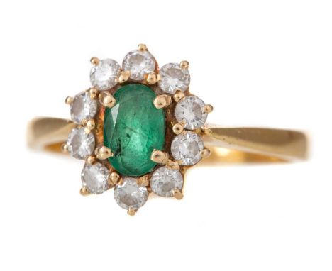 EMERALD AND DIAMOND RING set with central oval emerald within a diamond halo totalling approximately 0.30 carats, in eighteen