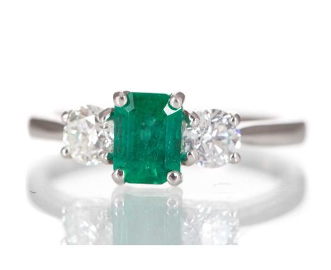 EMERALD AND DIAMOND THREE STONE RING set with central emerald of approximately 0.82 carats, flanked by diamonds totalling app