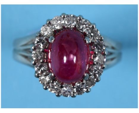 A white coloured metal ring, set a central Burmese cabochon ruby of approx. 4.2ct within a surround of diamonds, apparently u