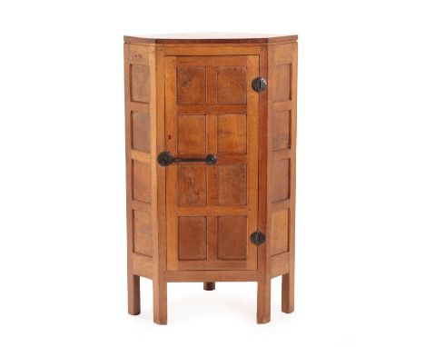 Robert Mouseman Thompson (1876-1955): An English Oak Panelled Floor Standing Corner Cupboard, 1930's, the door with wrought i