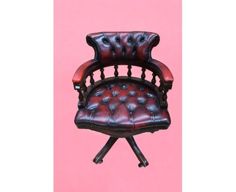 A mid 20th Century ox blood leather button back office/desk chair on four splayed leg supports on castors.