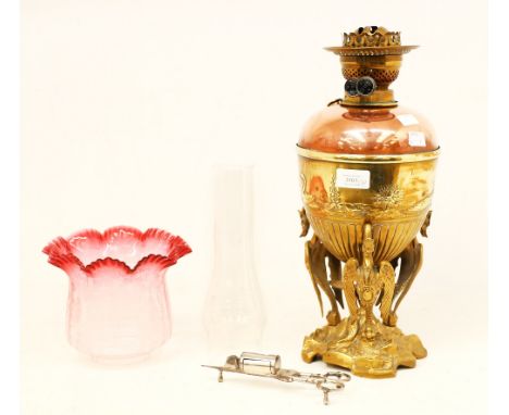 An early 20th century brass and copper oil lamp, embossed with swan decoration, raised on three cast cranes standing on a roc