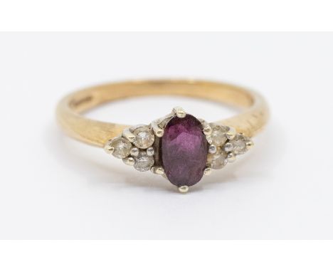 A ruby and diamond 9ct gold stone set ring, comprising an oval mixed cut central ruby approx 4 x 7mm, size N1/2, total gross 