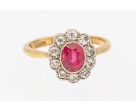 A synthetic ruby and diamond 18ct gold ring, comprising an oval mixed cut central stone measuring 6.6 x 5.1mm, within a plati