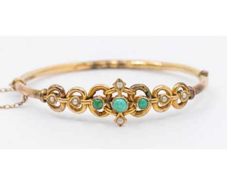 An early 20th century turquoise and 9ct gold bangle, the front set with three graduated round cabochon turquoise with pearl s