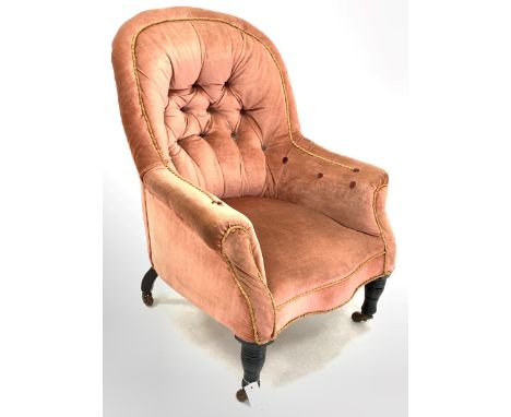 Victorian armchair, upholstered in buttoned faded velvet, with shaped apron, raised on ebonised turned front supports and bra