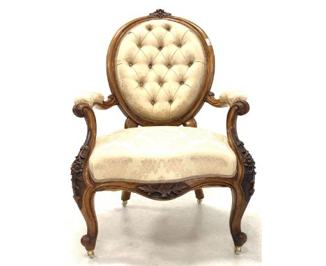Late Victorian mahogany open armchair, floral carved crest rail over oval buttoned back, scrolled and leaf carved arm termina