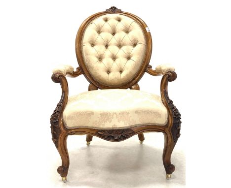 Late Victorian mahogany open armchair, floral carved crest rail over oval buttoned back, scrolled and leaf carved arm termina