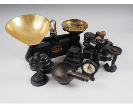 A black metal and brass balance with weights, a black metal pestle and mortar, a salt and pepper grinder, and other similar i